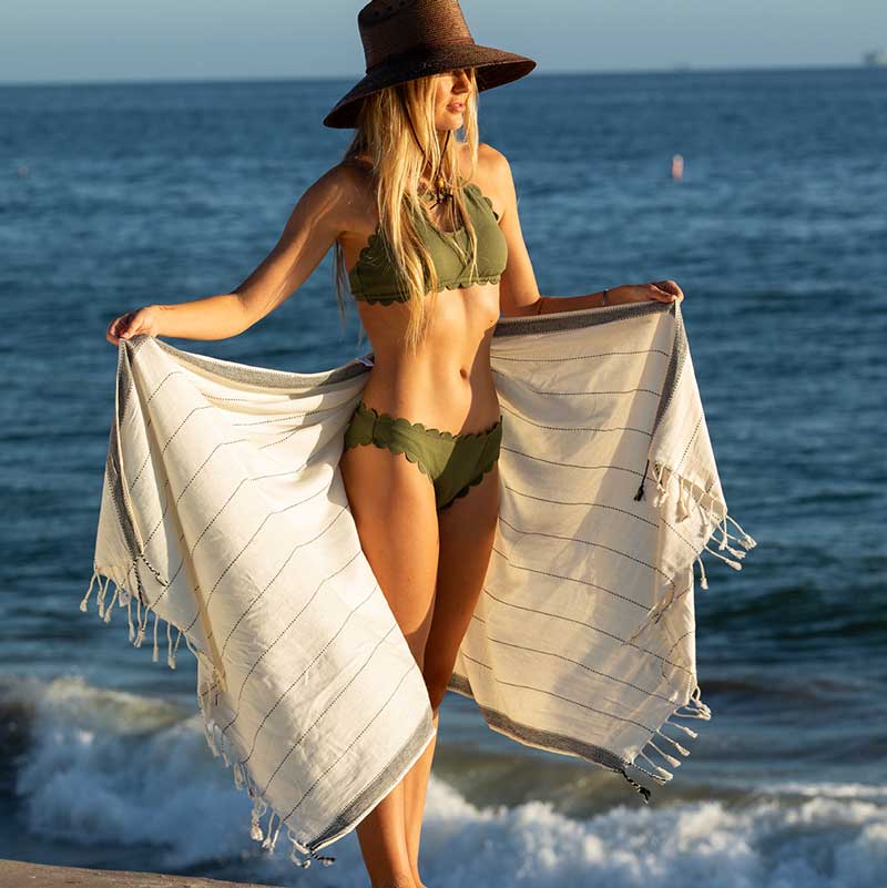 Two women at the beach wearing Riviera Turkish Towels as sarongs